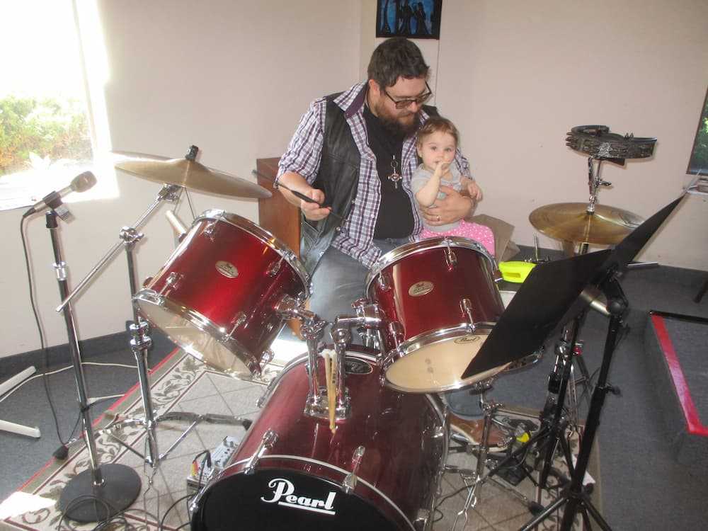 A man and little girl playing drums together at Gloucester church.