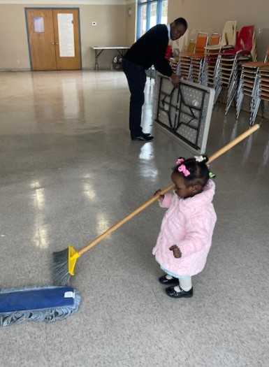 A little girl playing with a mop.