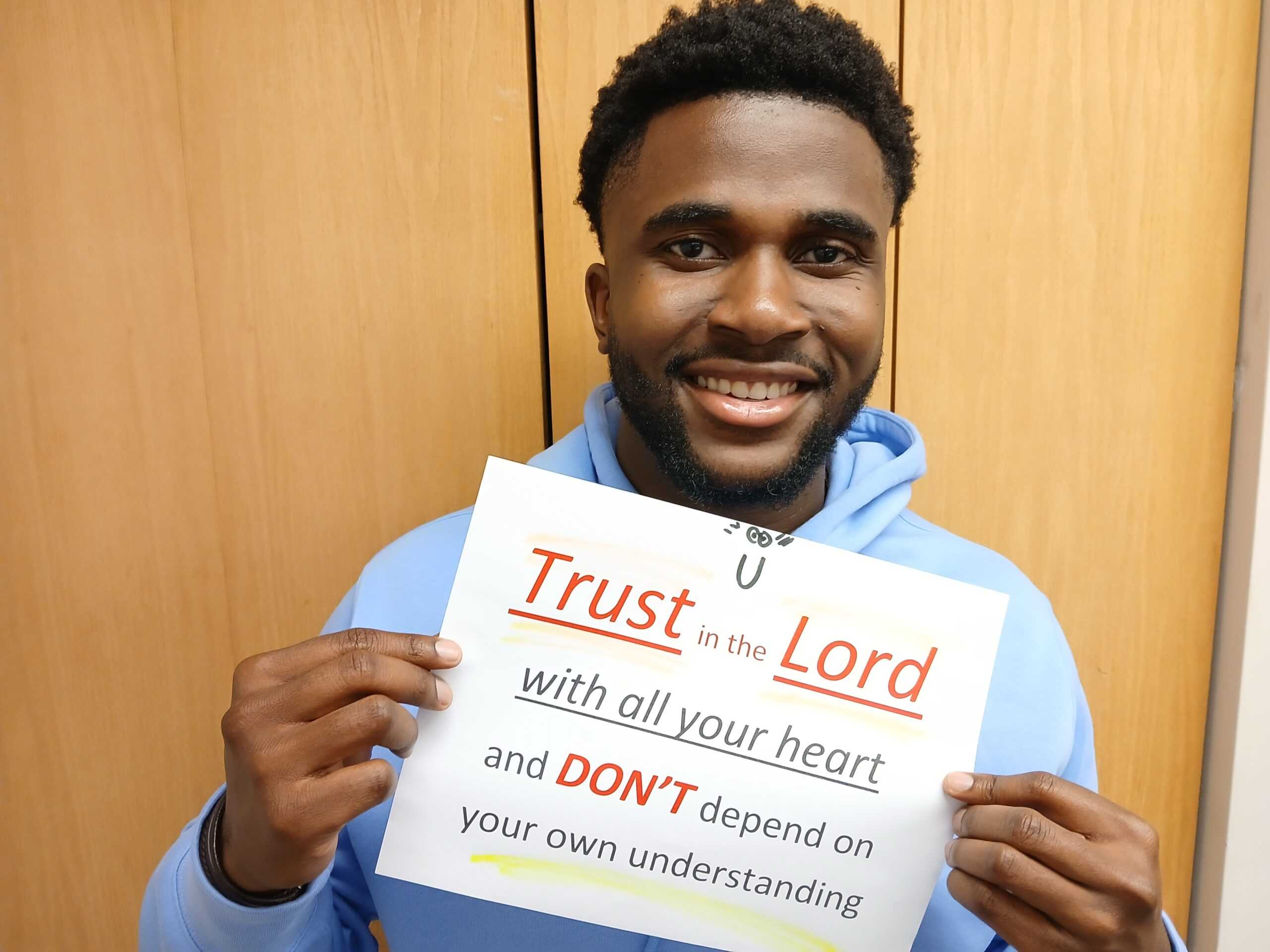 A man holding a sign that says 'Trust in the Lord'